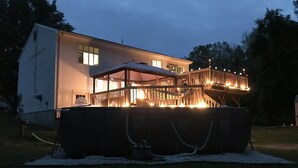 Una casa con terraza techada e hidromasaje al frente.