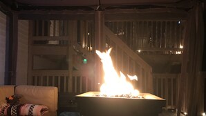 Una habitación con una chimenea grande y abierta, un sofá y una escalera.