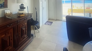 Ein Wohnzimmer mit Blick auf den Strand, einem Holzschrank, einer Lampe und einem Sessel.