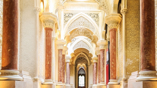 An ornate hallway with columns and intricate ceiling designs.