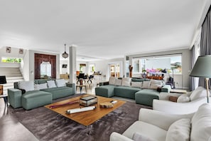 Un salon spacieux avec un grand canapé d’angle, une table basse et une vue sur l’extérieur.