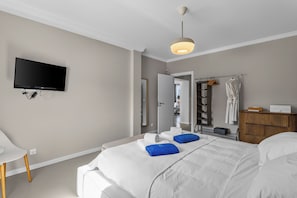 Una habitación de hotel con cama, televisor, armario y espejo.