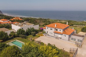 Un barrio residencial con casas, una piscina y vistas al mar.