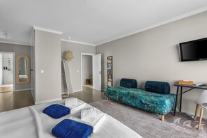 A modern bedroom with a bed, a TV, and a bathroom visible. - Oceanfront Villa at Praia Grande · Heated Pool (Colares)