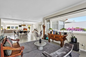 A spacious living area with a sofa, a coffee table, and a side table with books and decorative items. - Oceanfront Villa at Praia Grande · Heated Pool (Colares)