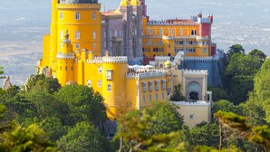 A large, historic castle with multiple towers and domes, surrounded by lush greenery. - Oceanfront Villa at Praia Grande · Heated Pool (Colares)