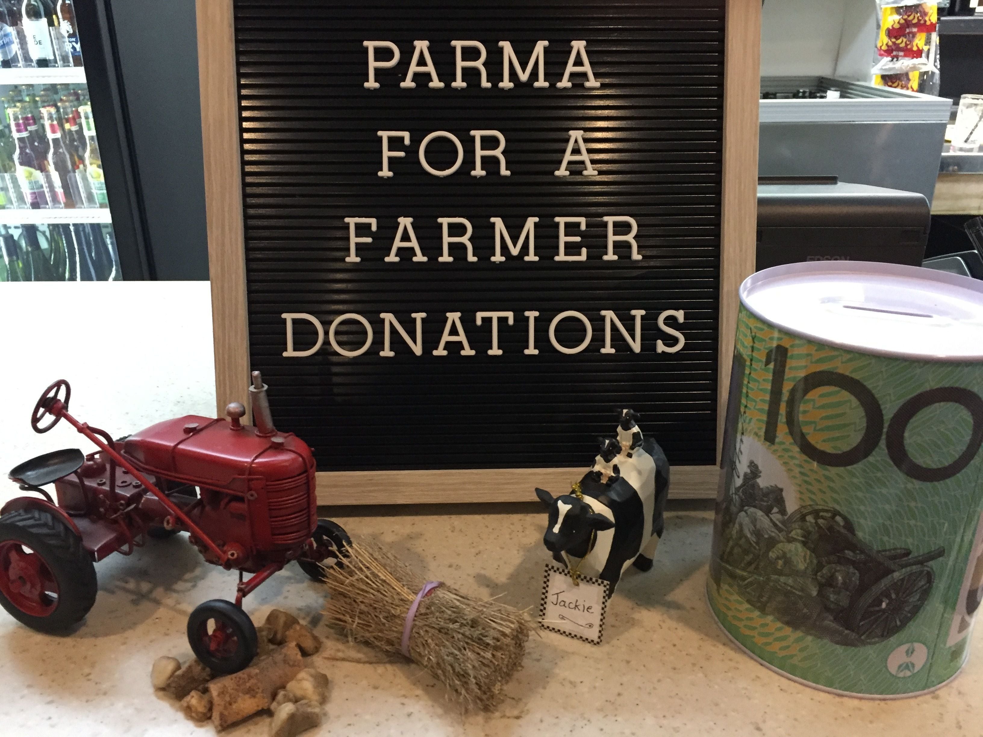 A display with a sign reading "PARMA FOR A FARMER DONATIONS" and a vintage tractor model.