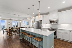 A modern kitchen with white cabinets, stainless steel appliances, and a large island with bar stools.