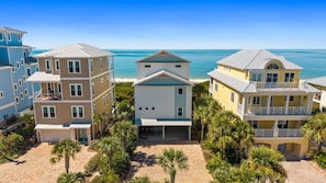 A beachfront property with multiple buildings, including a central house with a balcony and a smaller structure with a covered porch.