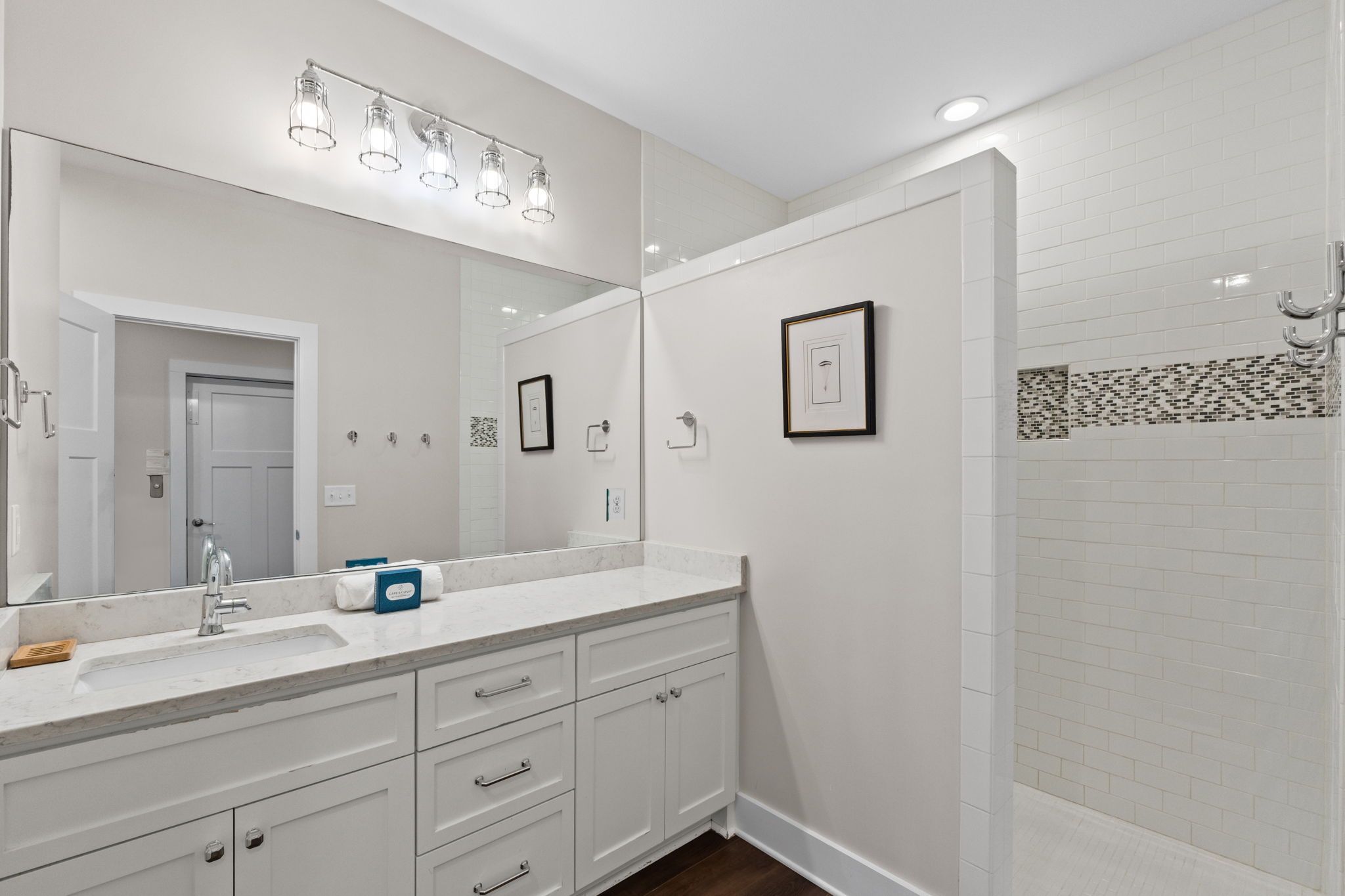 A modern bathroom with a large mirror, a sink, and a shower area.