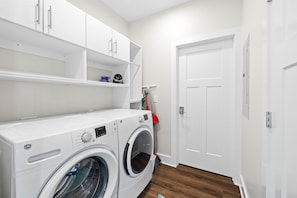 A laundry room with a front-loading washing machine, a dryer, and a door.
