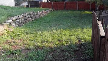 A backyard with a stone wall, a wooden fence, and a grassy area.
