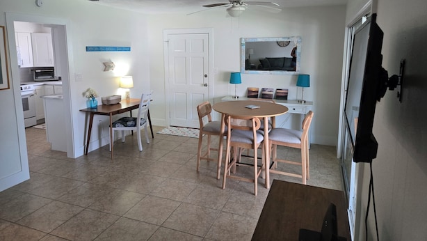 A compact living space with a dining area, kitchenette, and a ceiling fan.