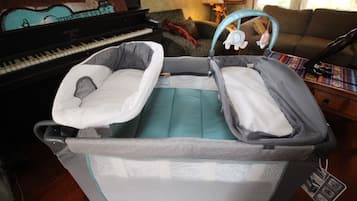 Relax in this inviting living room with a convertible bassinet, upright piano, and comfortable couch.
