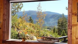 A wooden window frame with a view of mountains and trees.