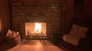 A cozy room with a stone fireplace, a wooden bench, and a cushioned chair.
