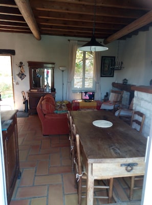 A rustic dining area with a wooden table and chairs, a sofa, and a television. - Medieval charm and soaring vistas in the heart of Provence: what's not to love? (Vaison-la-Romaine)