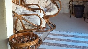 Una habitación acogedora con pared de piedra, techo de madera y sofá de mimbre con cojines.