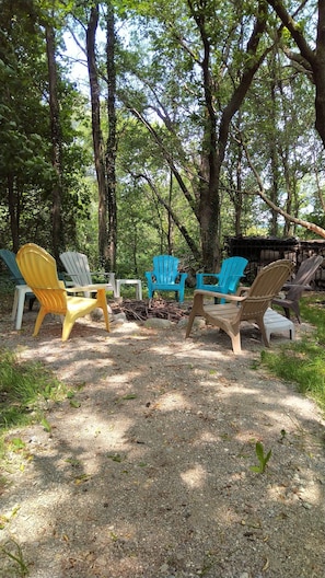 Un área boscosa con varias sillas Adirondack de diferentes colores.