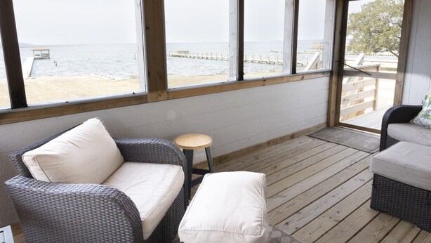 Un espacio de estar al aire libre cubierto con mobiliario de mimbre y vistas a la playa.