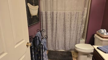 A bathroom with a toilet, a shower curtain, and a bathtub.