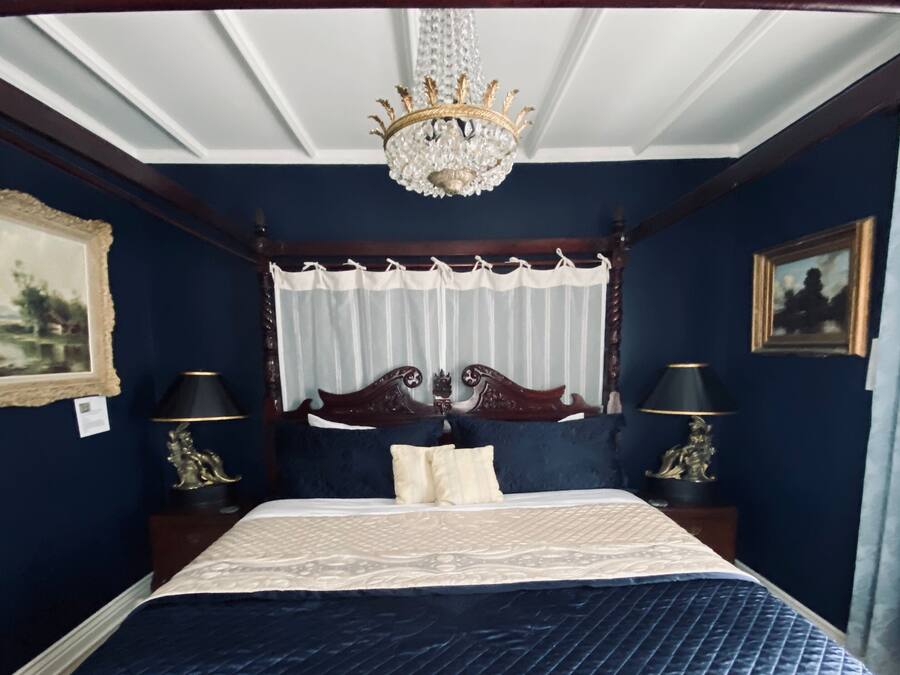 Una cama con dosel y doselajes, con un edredón azul oscuro.