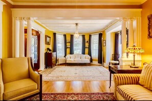 A spacious living room with a large rug, a sofa, and a chair. - 1000 Islands B&B – The Bulloch House (Gananoque)