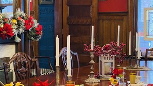 Un comedor con una mesa de madera dispuesta para una comida, una araña y una decoración navideña.