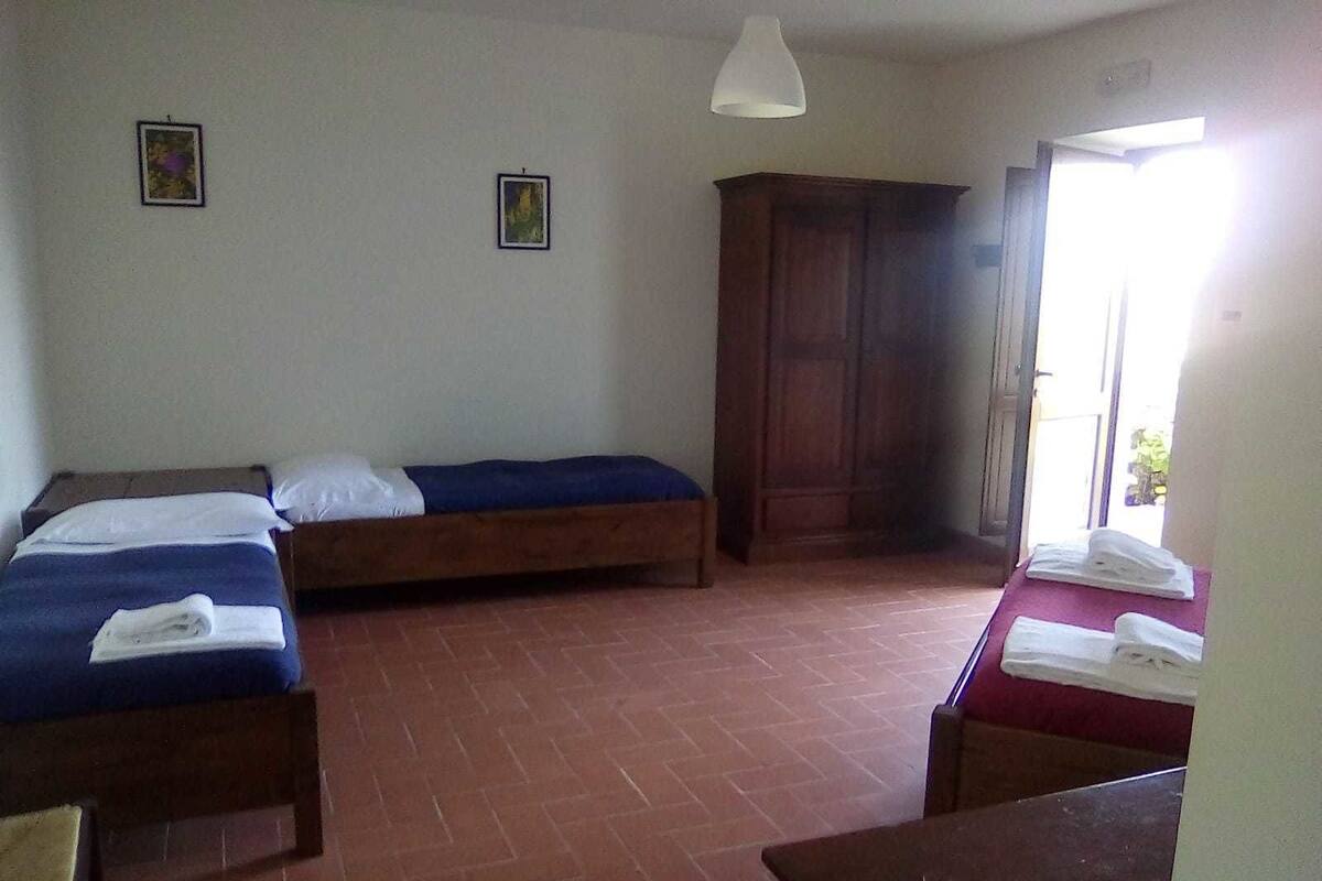 A room with two beds, a wooden wardrobe, and a table with towels.