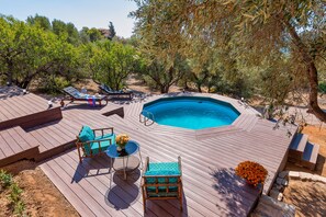 A wooden deck with a swimming pool, lounge chairs, and a table with flowers. - Lagonisi Villa Afroditi (Saronikos)