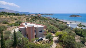 A Mediterranean-style villa with a flat roof, surrounded by olive trees and a clear view of the sea. - Lagonisi Villa Afroditi (Saronikos)