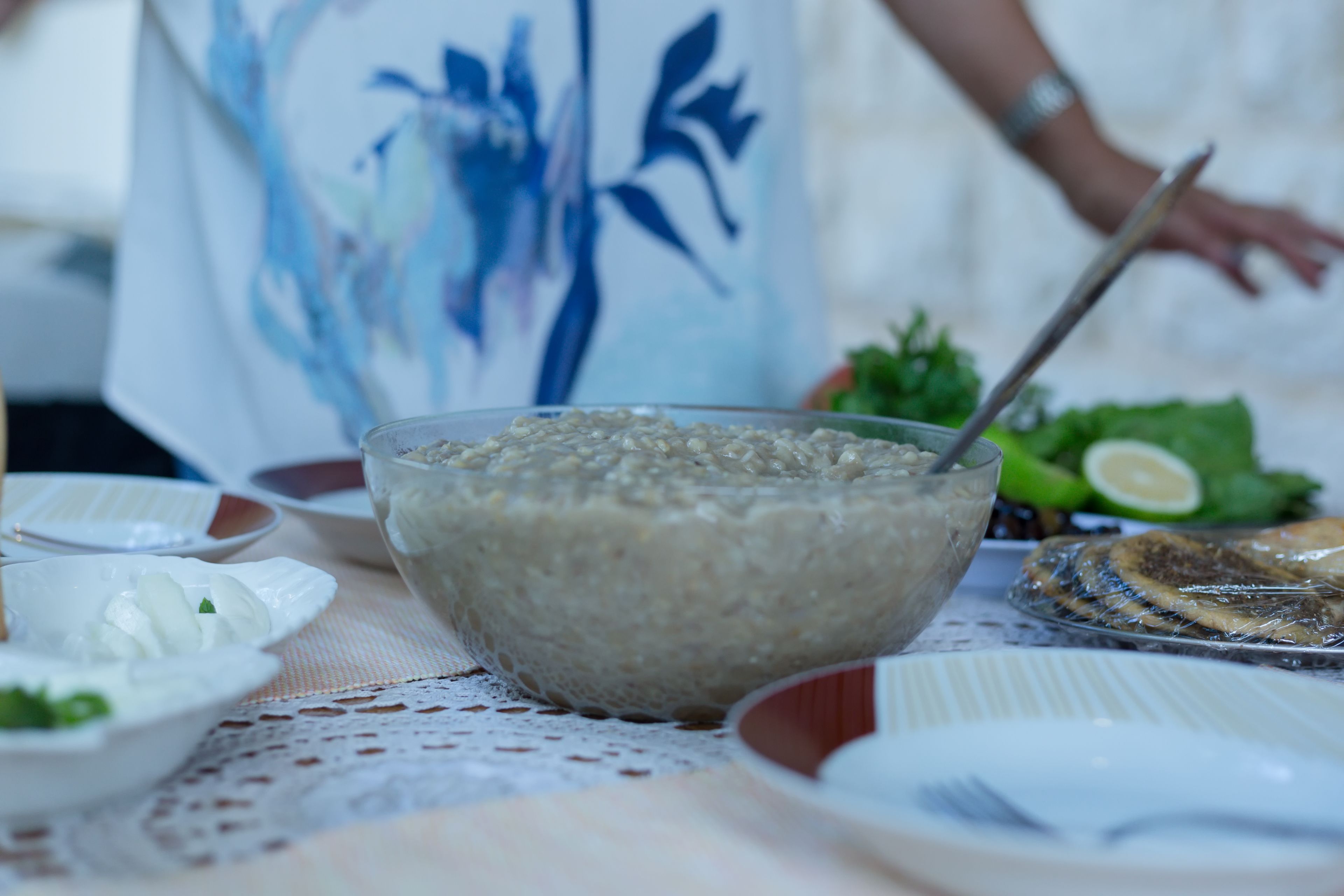 A table with various dishes, including a bowl of food, plates with food, and a fish on a plate.