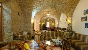 Un interior amb parets de pedra, zona de menjador, sofàs i televisió.