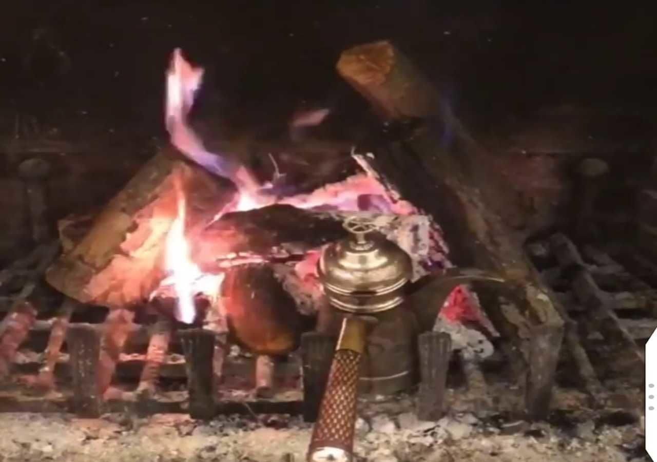 A campfire with logs and a metal pot.