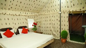 A tented room with a bed, red pillows, a potted plant, and a window. - Kumbha Kamps (Prayagraj)