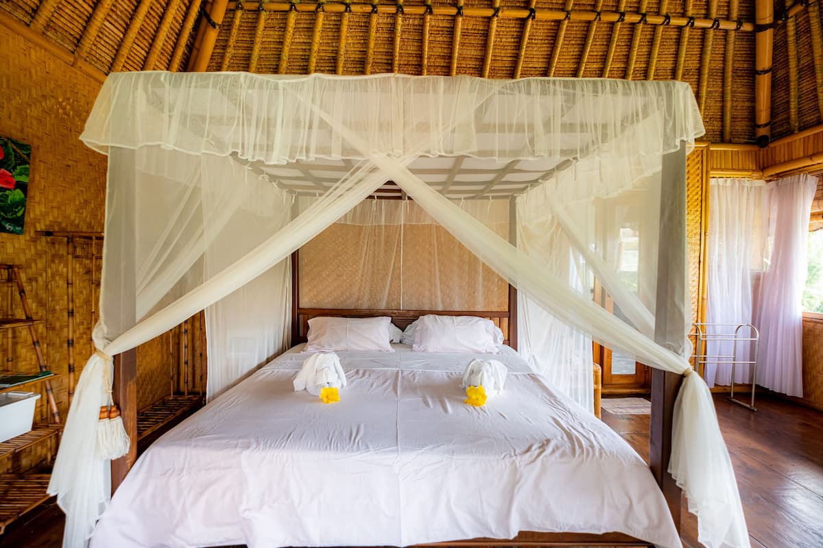 A bed with a canopy, white bedding, and two towels with yellow flowers.