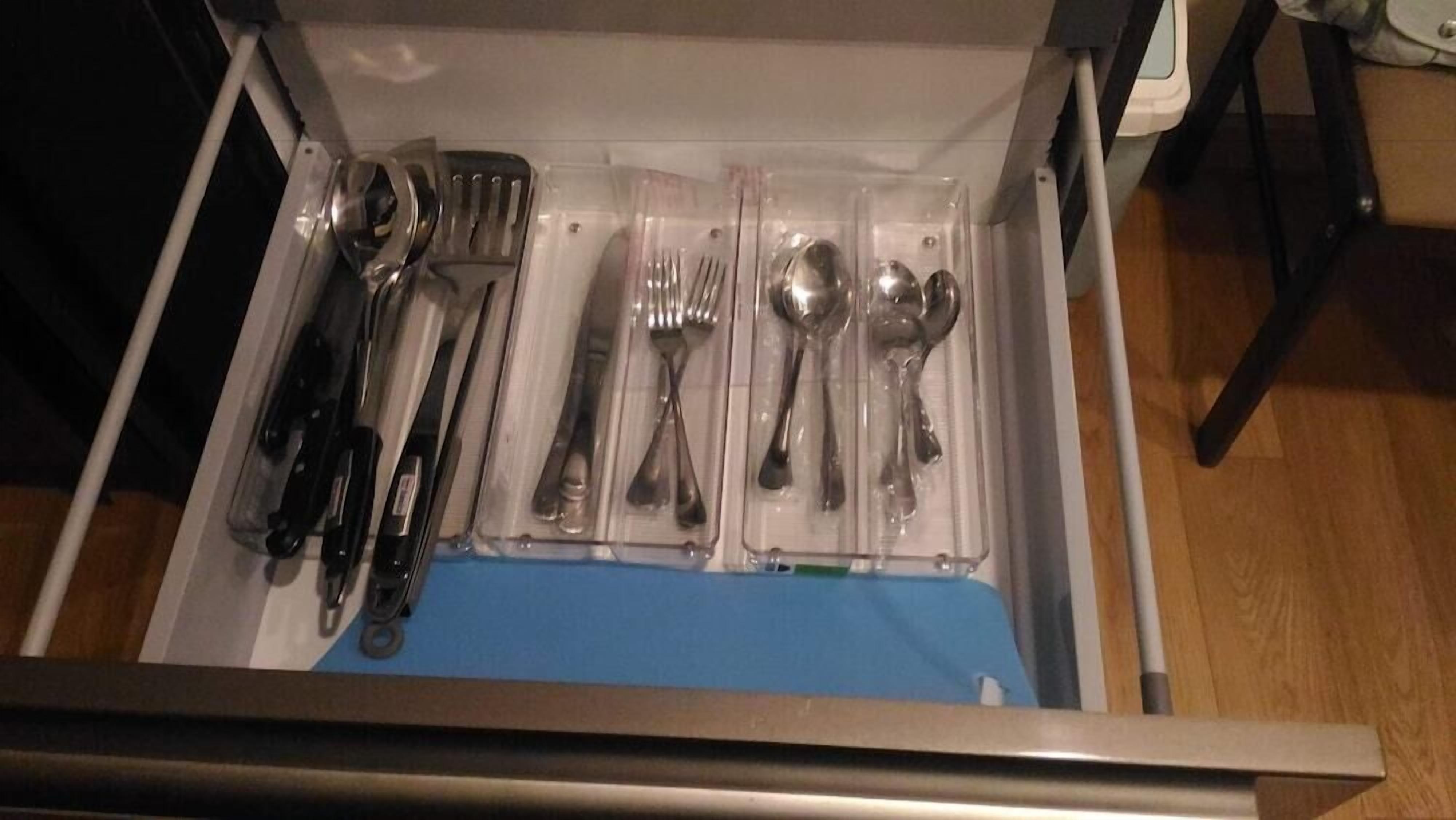 A drawer containing neatly arranged cutlery including forks, knives, and spoons.