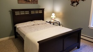 A bedroom with a dark wooden bed, a white bedspread, a nightstand with a lamp, and a wall-mounted bear picture. - Your Home away from Home. Large Groups Welcome (Hamden)