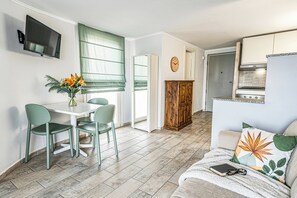 A compact living space with a dining area, kitchenette, and a sofa with a decorative pillow.