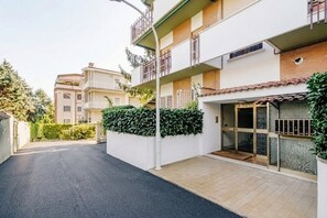 A residential building with a gated entrance, a balcony, and a small garden area.
