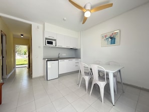 A modern kitchen with white cabinets, a microwave, and a ceiling fan.