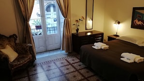 A hotel room with a bed, a chair, a dresser, a mirror, and a window with curtains. - B&B Aloi Rooms (Catania)