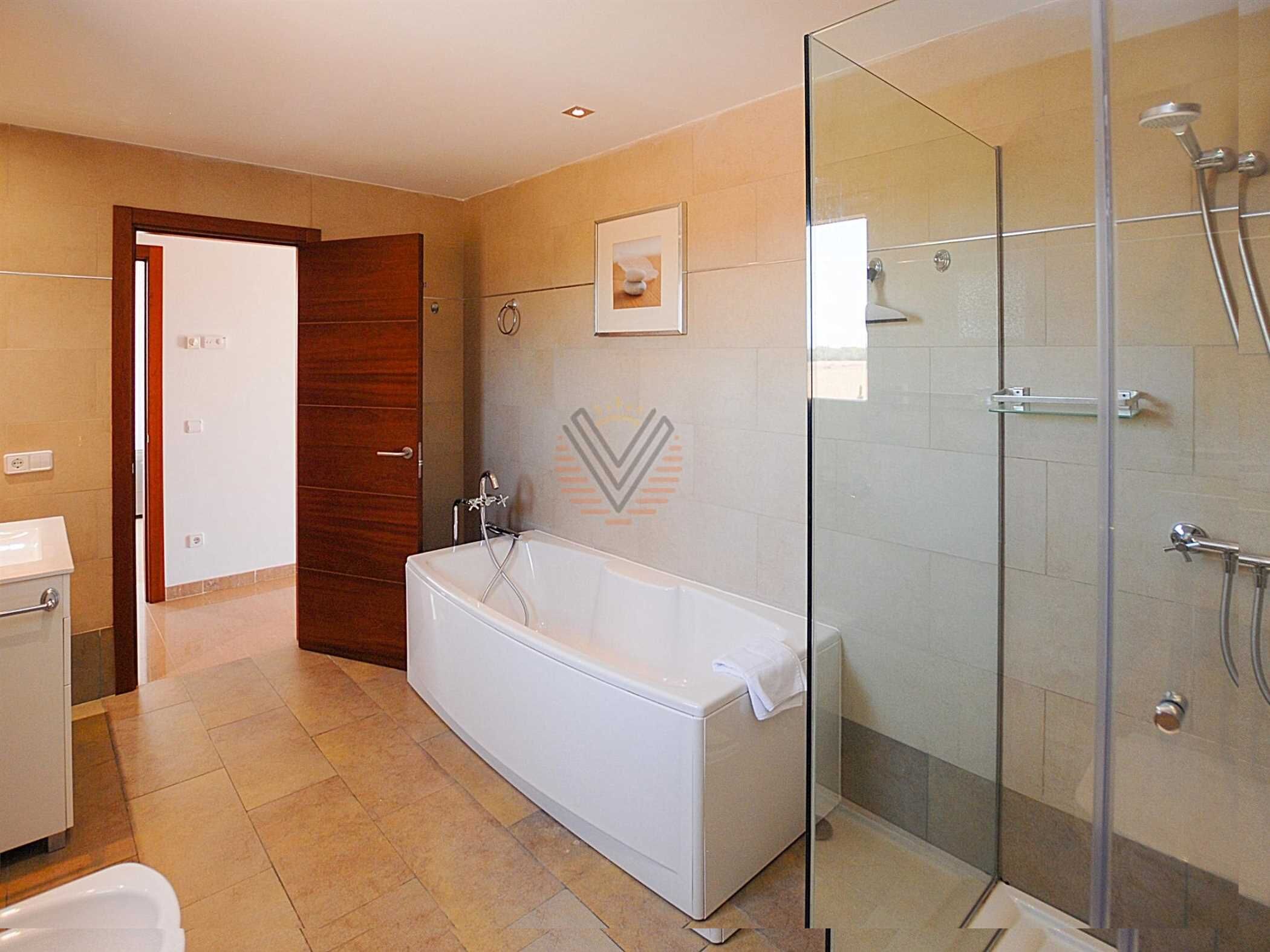 Ein modernes Badezimmer mit einer gläsernen Duschkabine, einer freistehenden Badewanne und einer Holztür.