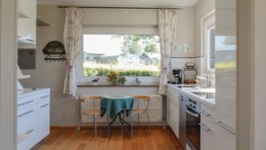 Cocina compacta con mesa, sillas, radiador y ventana con cortinas.