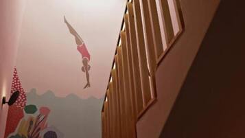 A staircase with wooden railings and a mural on the wall depicting a diver.