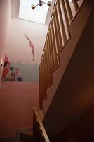 A staircase with wooden railings and a mural on the wall depicting a diver.