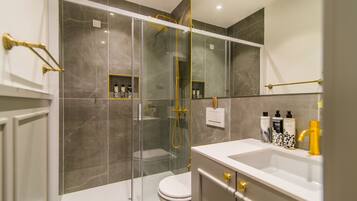 A modern bathroom with a glass-enclosed shower, a white toilet, and a vanity with a sink and mirror.