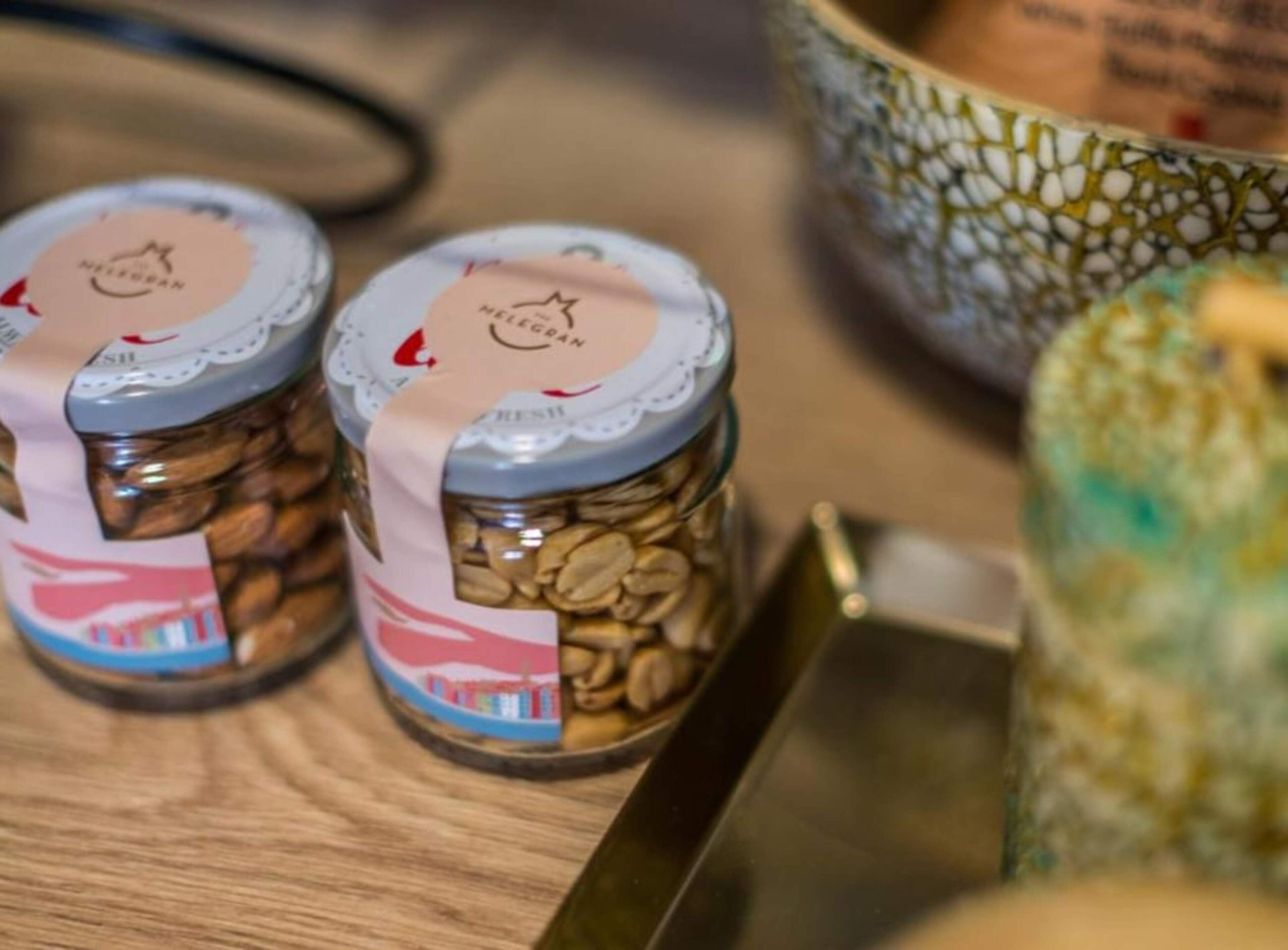 Dos tarros de granos de café con etiquetas, una taza de cerámica y una superficie de madera.