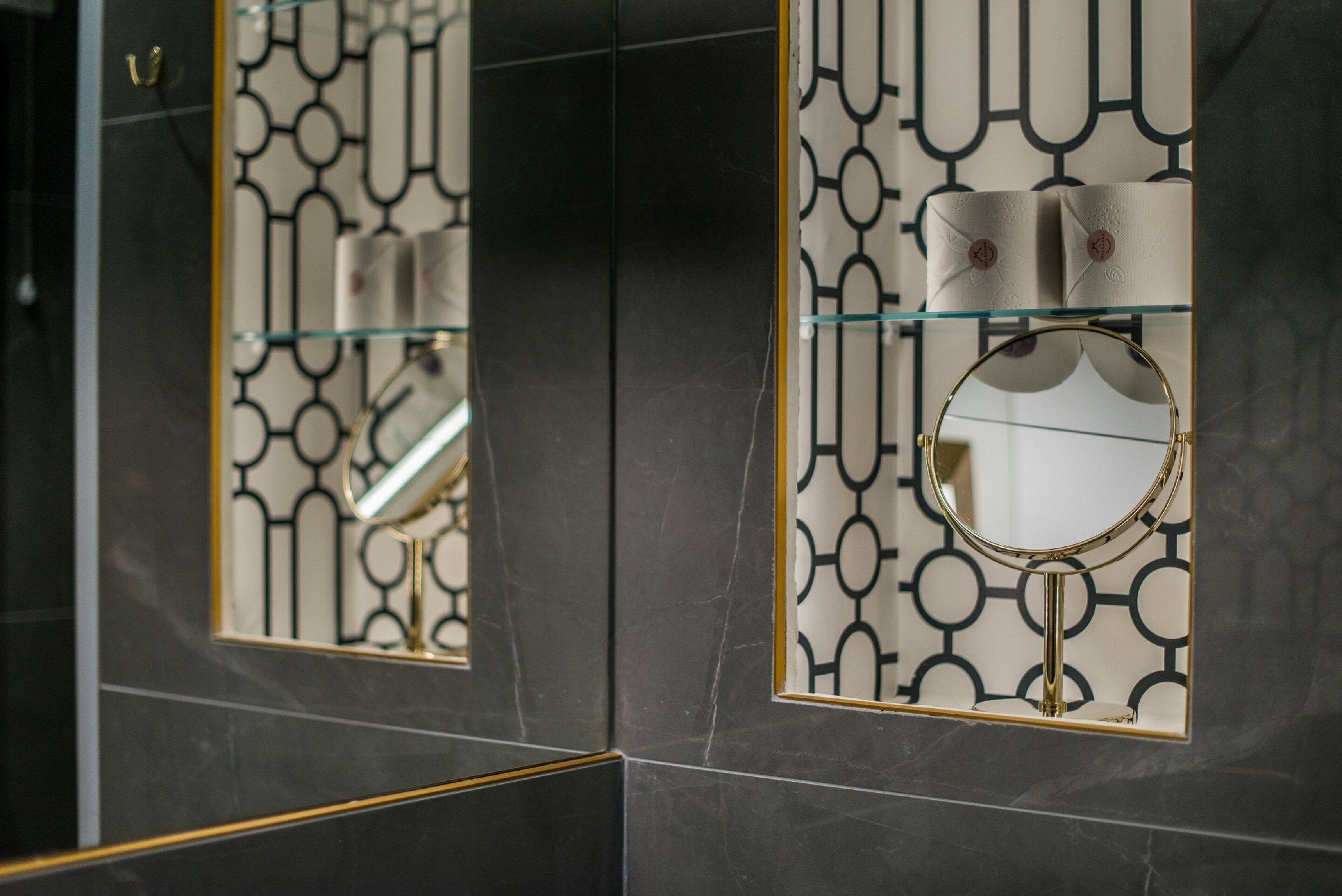 A bathroom with a mirror, a towel rack, and a patterned wall.