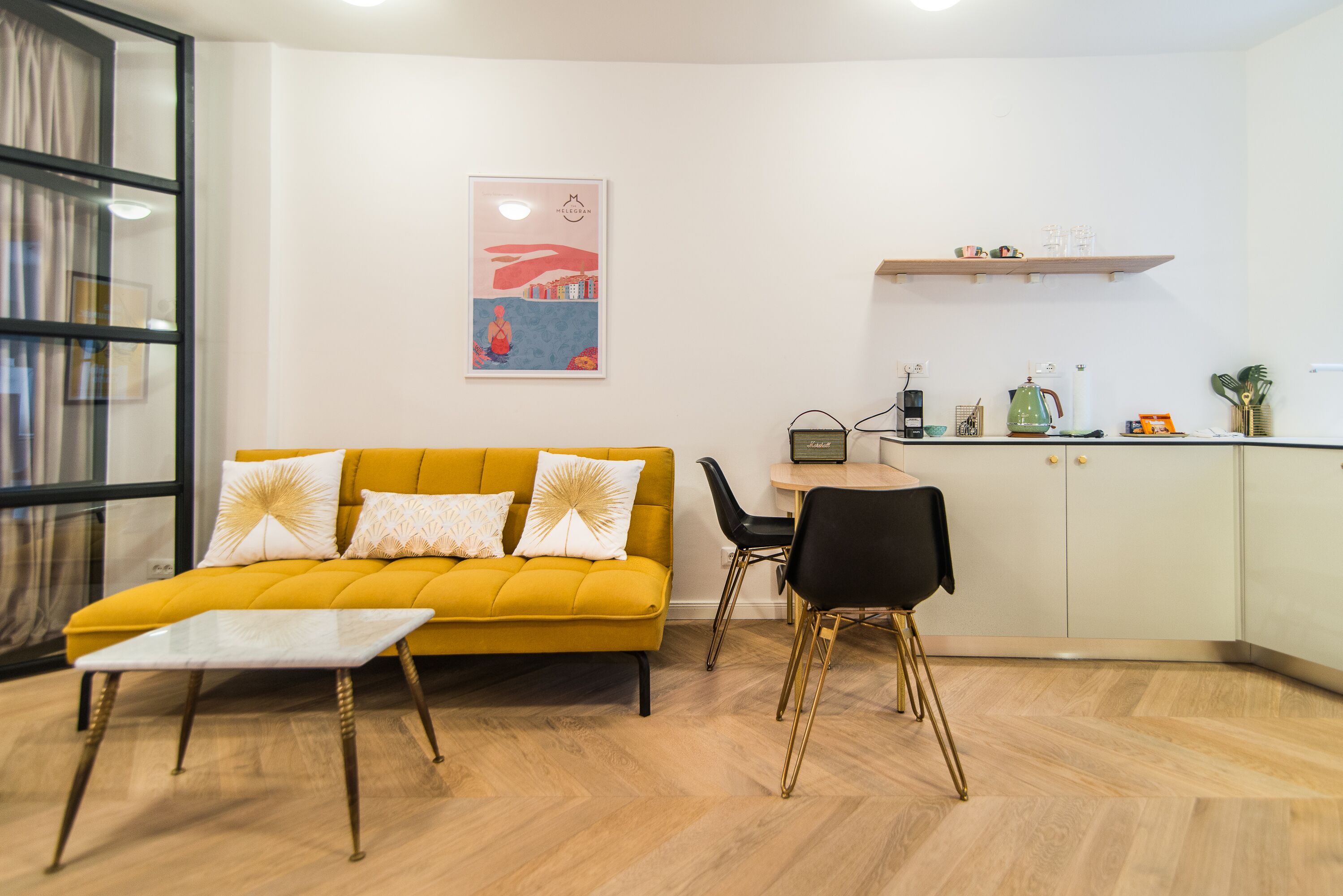 Una sala de estar moderna con un sofá amarillo, una mesita y una zona de cocina con una mesa de comedor y sillas.